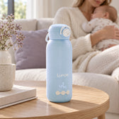Lunae flessenwarmer thuis met ouder en baby op de achtergrond